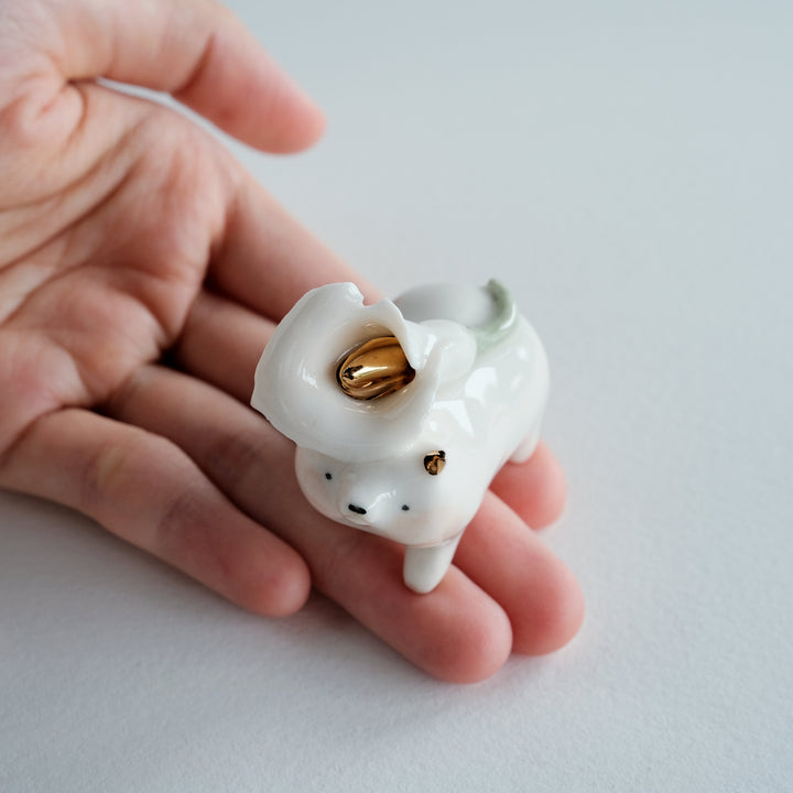Small white ceramic animal figurine held in a hand against a light background
